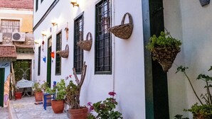 Uma rua estreita com edifícios brancos, plantas em vasos e cestos suspensos.