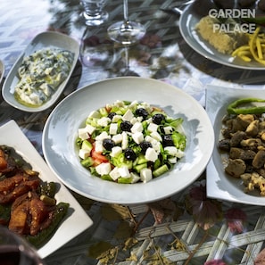 A table set with various dishes including a salad, a plate of meat, and a bowl of rice. - Garden Palace Boutique Hotel (Kusadasi)