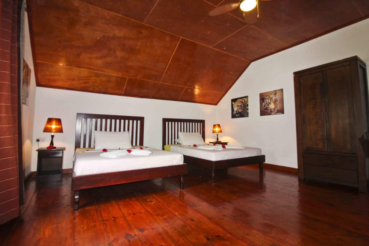 Ein Zimmer mit zwei Holzbettgestellen, einem Deckenventilator und einem Kleiderschrank.