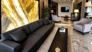 A modern living room with a black sofa, a coffee table, and a large wall art piece. - Laodikya Otel (Denizli)