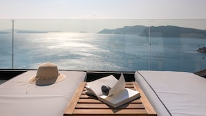 Un balcón con vista al mar, un sombrero y un libro abierto.