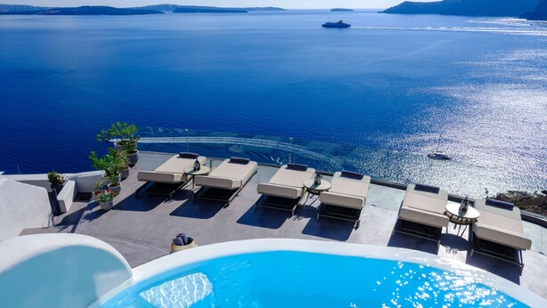 Zona de piscina con sillones de descanso y vista al mar.