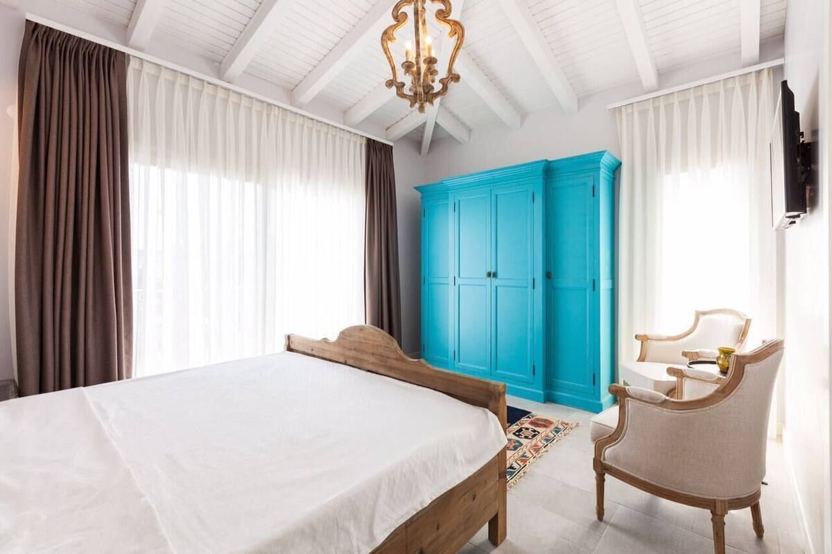 Ein Schlafzimmer mit einem großen Bett, einem blauen Kleiderschrank und einem Sessel.