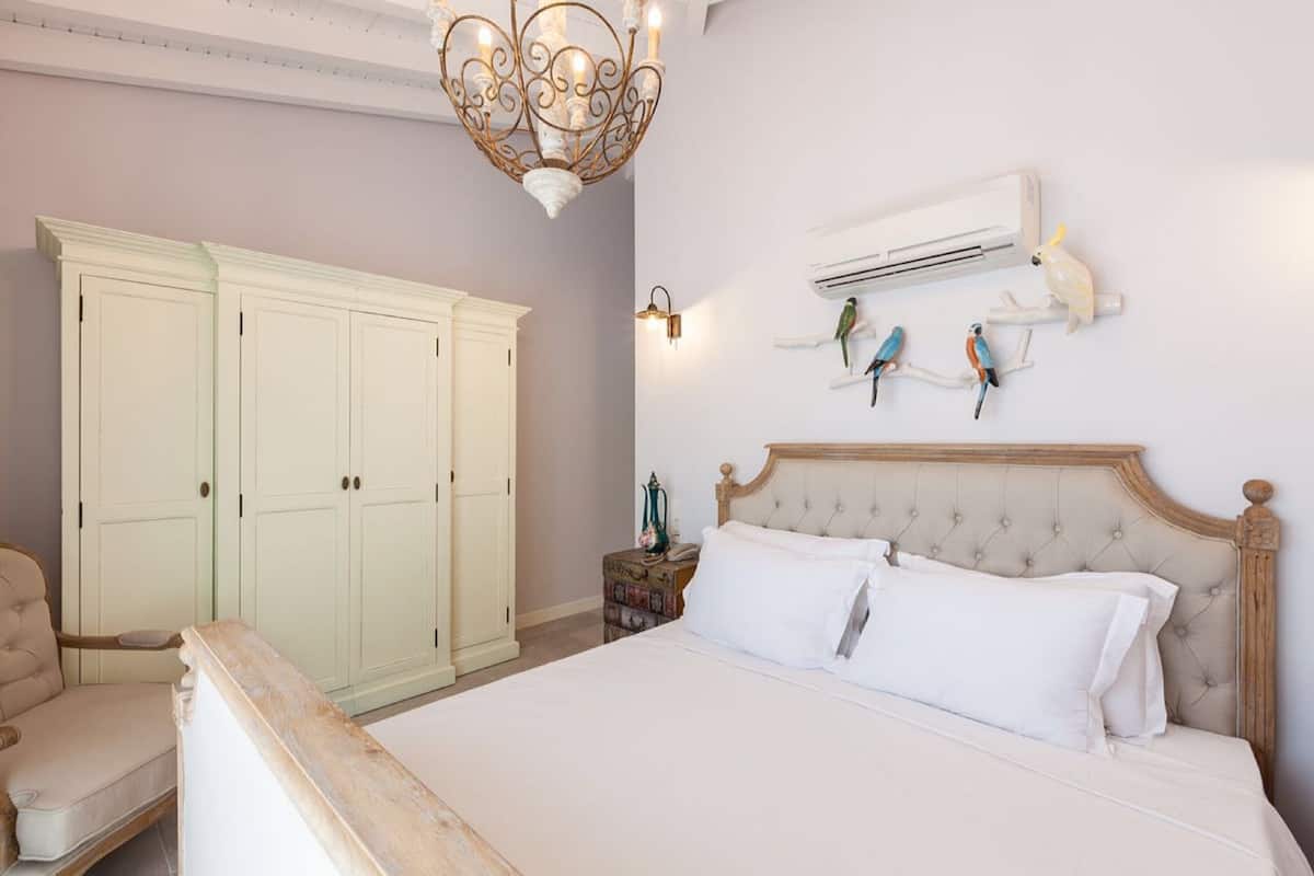 Ein Schlafzimmer mit einem Bett, einer Kristallleuchtre, einer Klimaanlage und Vogel-Figuren an der Wand.