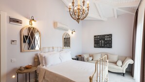 A bedroom with a bed, a sofa, a chandelier, and wall-mounted lights. - Alacaat Otel (Cesme)