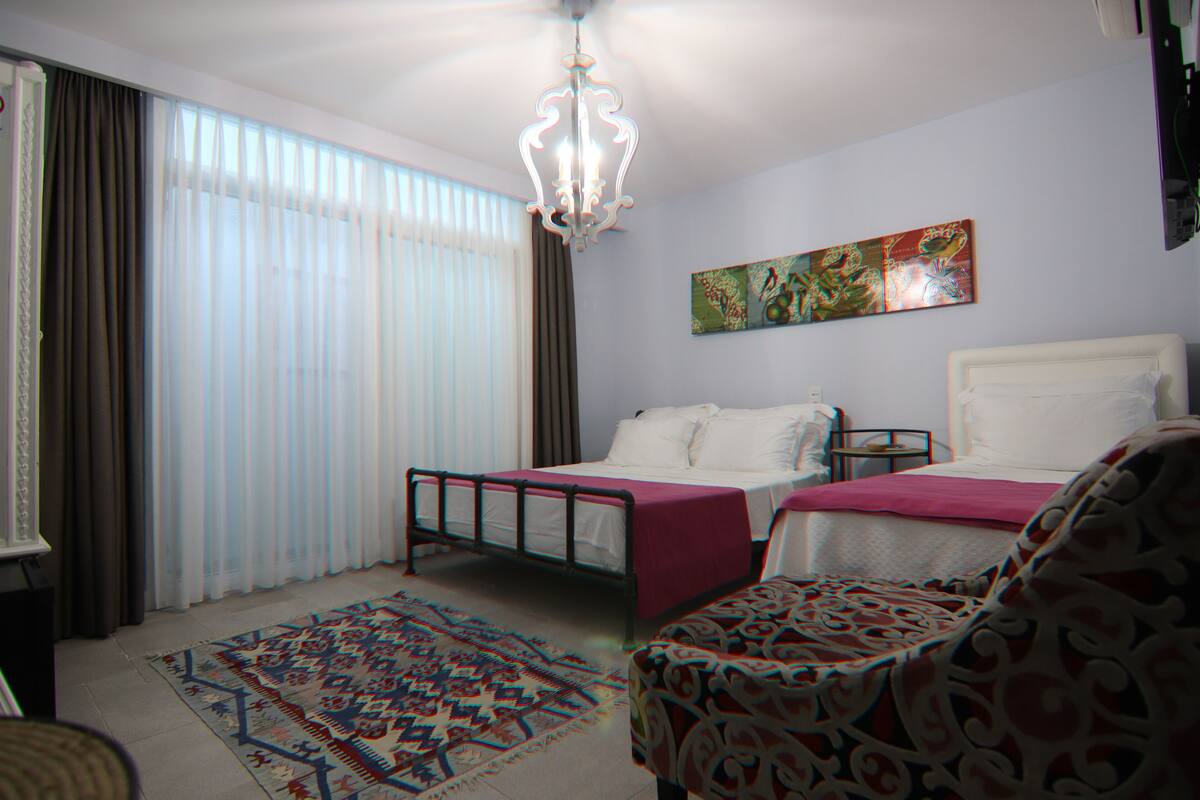 Ein Schlafzimmer mit zwei Betten, einer Kristallleuchter, einem gemusterten Teppich und einem Gemälde an der Wand.