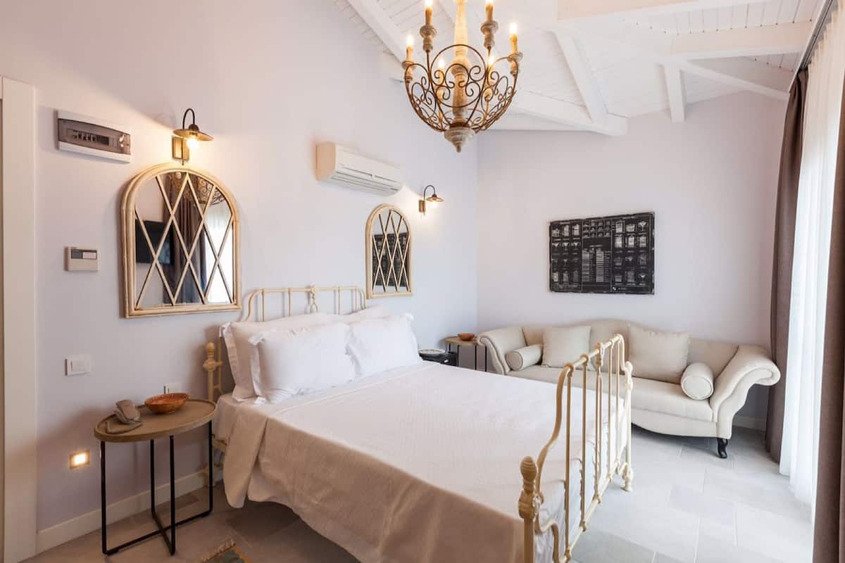Ein Hotelzimmer mit Bett, einer Couch, einem Chandelier und Wandleuchten.