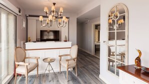 A modern kitchen with a central island, two chairs, a small table, and a chandelier. - Alacaat Otel (Cesme)