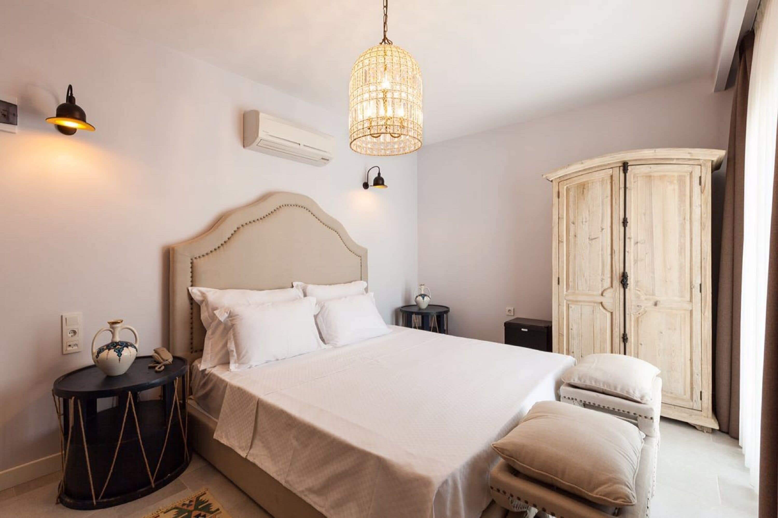 A bedroom with a bed, bedside tables, a wardrobe, and a hanging light fixture.