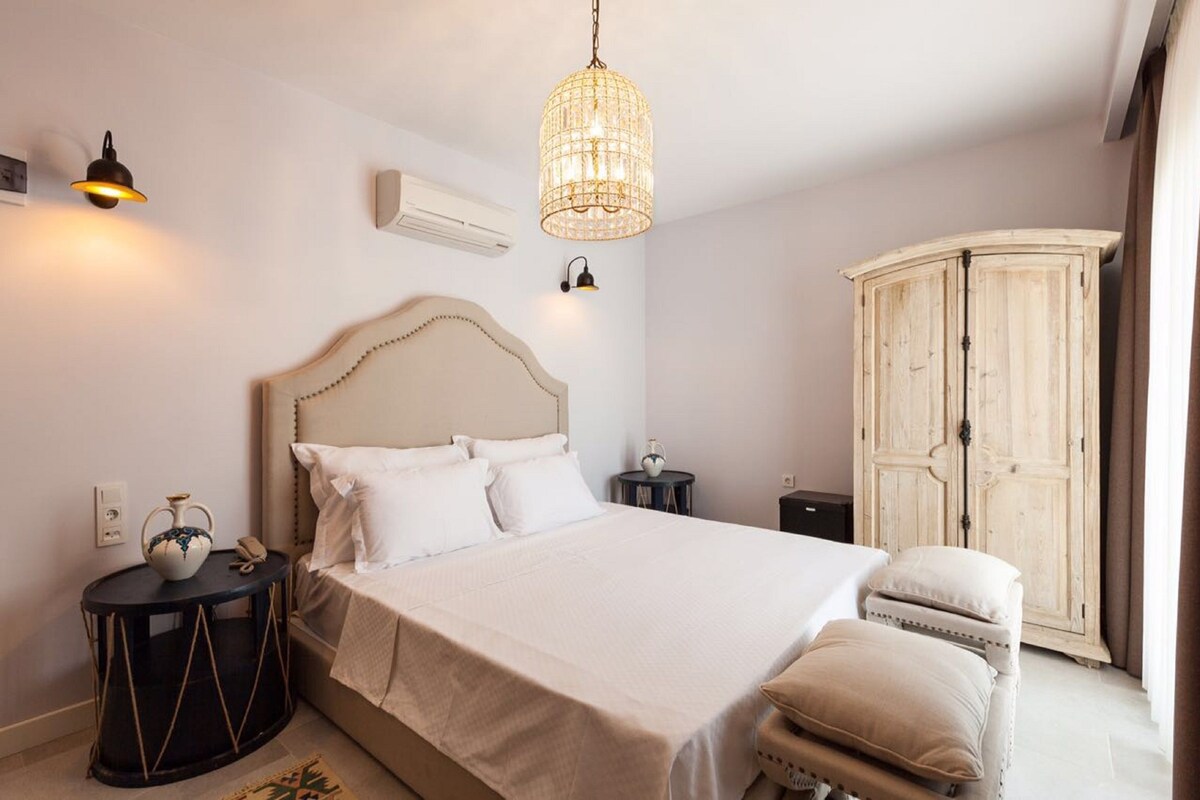 A bedroom with a bed, bedside tables, a wardrobe, and a hanging light fixture.