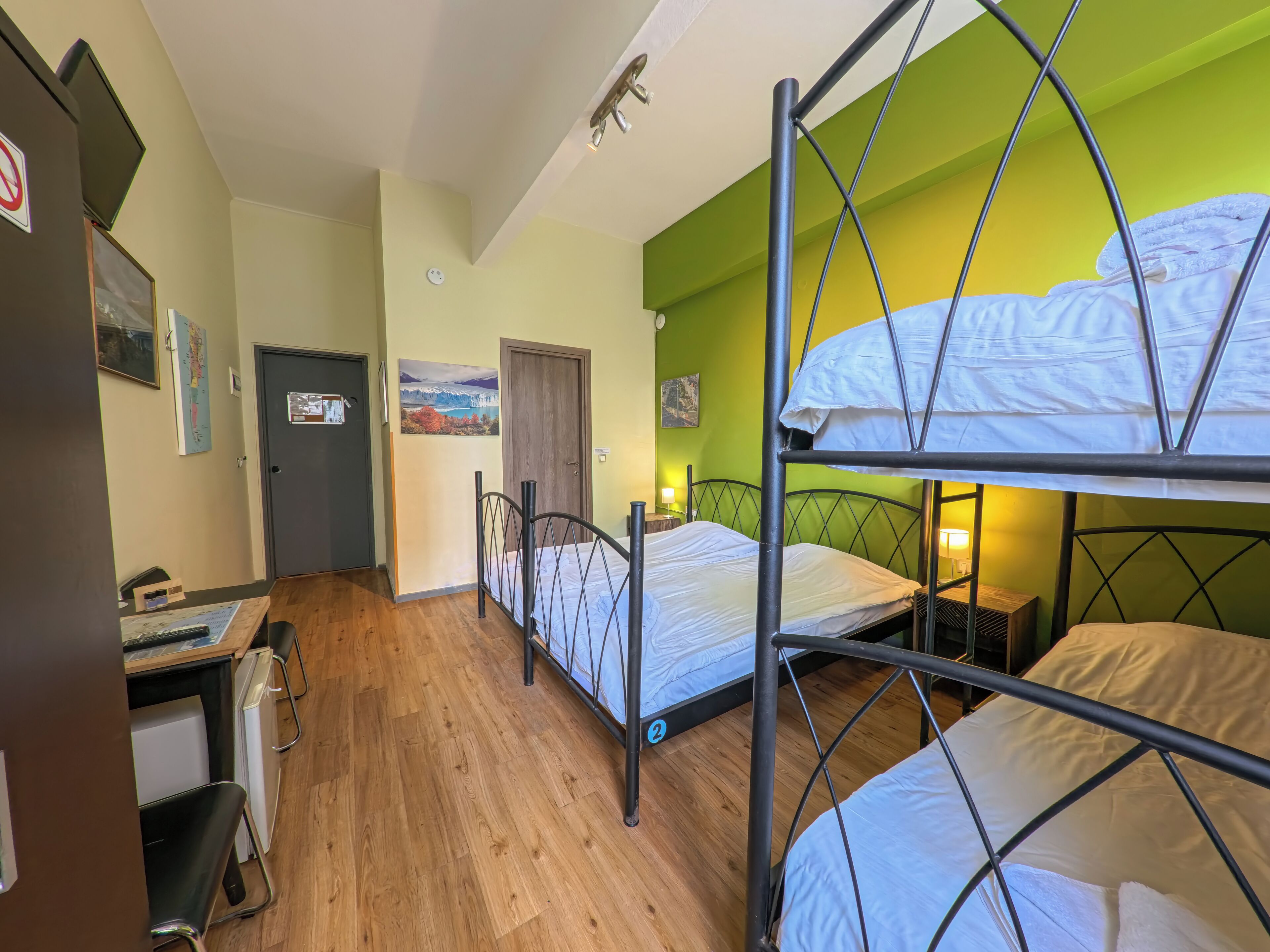 Habitación tipo dormitorio con literas, escritorio, silla y una pequeña kitchenette.