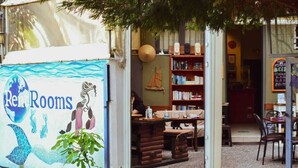 Een gezellige boekwinkel met een muurschildering van zeemeerminnen, houten boekenkasten en een kleine zithoek.