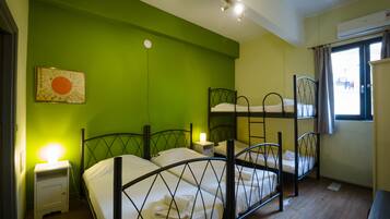 Una habitación con literas, una mesita de noche con lámpara y una ventana con cortinas.