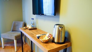 A small room with a wooden table, a chair, a television mounted on the wall, and a kettle. - Urla Zeytin Otel (Urla)