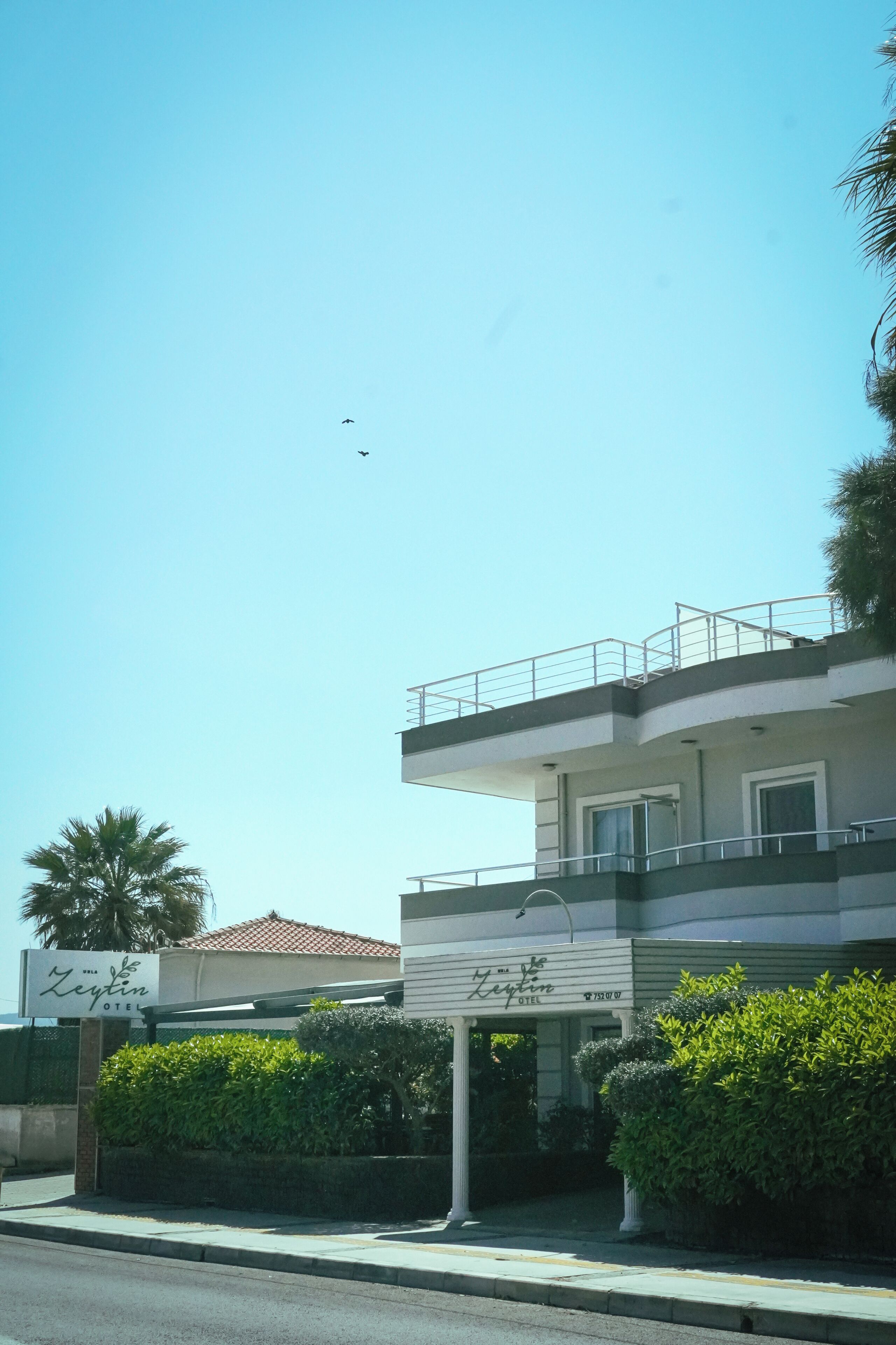 Un hotel con letrero, balcón y cielo despejado.