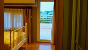 A bedroom with a balcony, wooden flooring, and a bed with a white headboard. - Urla Zeytin Otel (Urla)