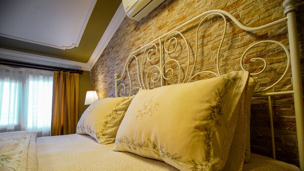 A bed with a metal headboard, a lamp, and a window with curtains. - Urla Zeytin Otel (Urla)
