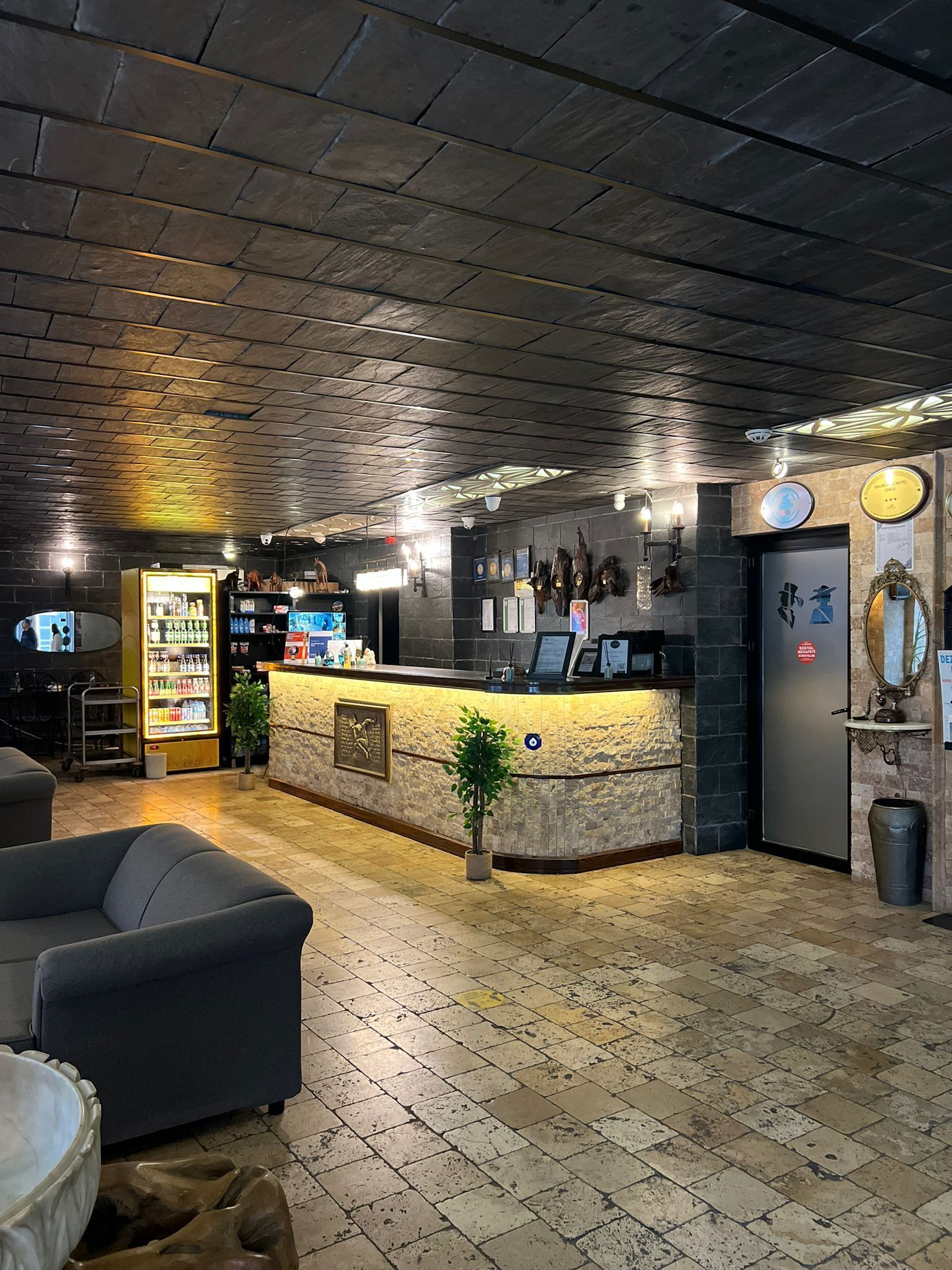 A reception area with a stone counter, a small plant, and a refrigerator.