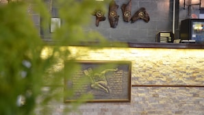 Un área de recepción con pared de piedra, un reloj y una obra de arte enmarcada.