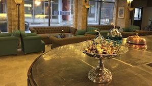 Un vestíbulo con una mesa de centro de vidrio, sofás verdes y un cuenco decorativo con dulces.
