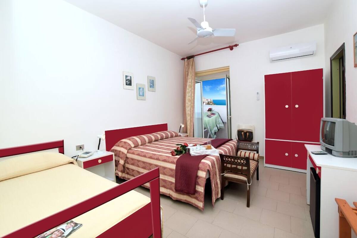 Un dormitorio con cama, escritorio, silla, televisor y armario.
