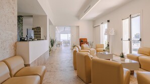 A modern hotel lobby with a reception desk, seating area, and large windows. - Hotel Peschici (Peschici)