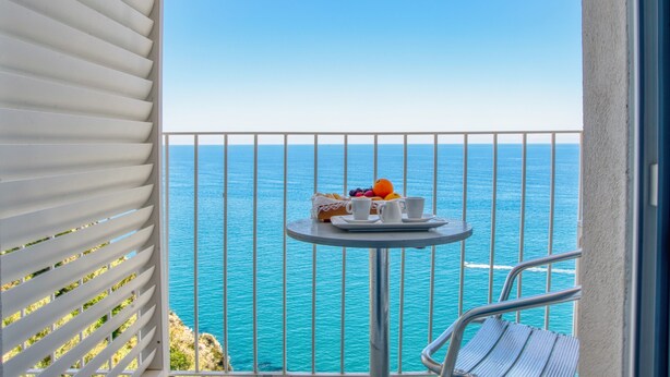 A balcony with a table set for breakfast, overlooking a clear blue sea. - Hotel Peschici (Peschici)