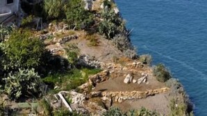 A coastal building with multiple levels, white exterior walls, and a rocky shoreline with vegetation. - Hotel Peschici (Peschici)