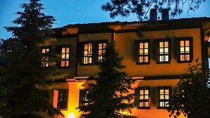 A two-story building with multiple windows, surrounded by trees.