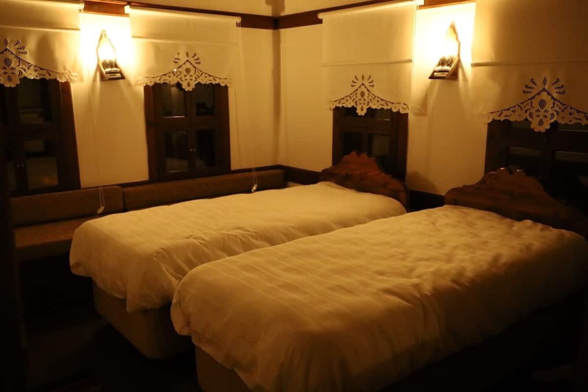 A hotel room with two beds, each with a wooden headboard, and a large mirror on the wall.