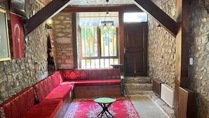 A cozy room with a stone wall, a red sofa, and a small table.