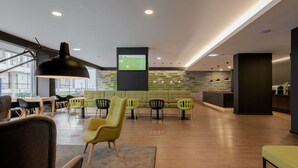 A modern lounge area with seating, a television screen, and a kitchen area. - Neat Hotel Avenida (Ponta Delgada)