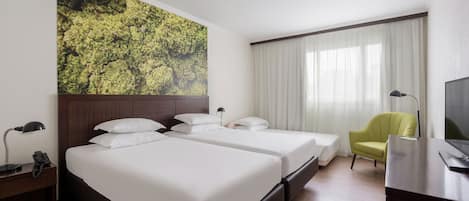 A hotel room with two beds, a desk, a chair, a TV, and a large window with curtains.