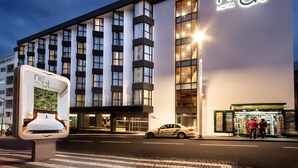 A modern hotel building with a prominent 'neat' sign, large windows, and a car parked in front. - Neat Hotel Avenida (Ponta Delgada)