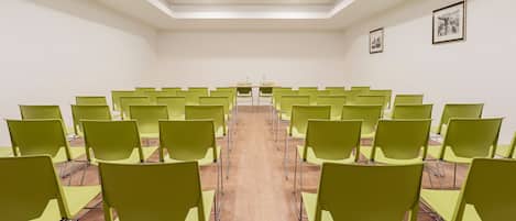 Un salón de conferencias con filas de sillas verdes y suelo de madera.