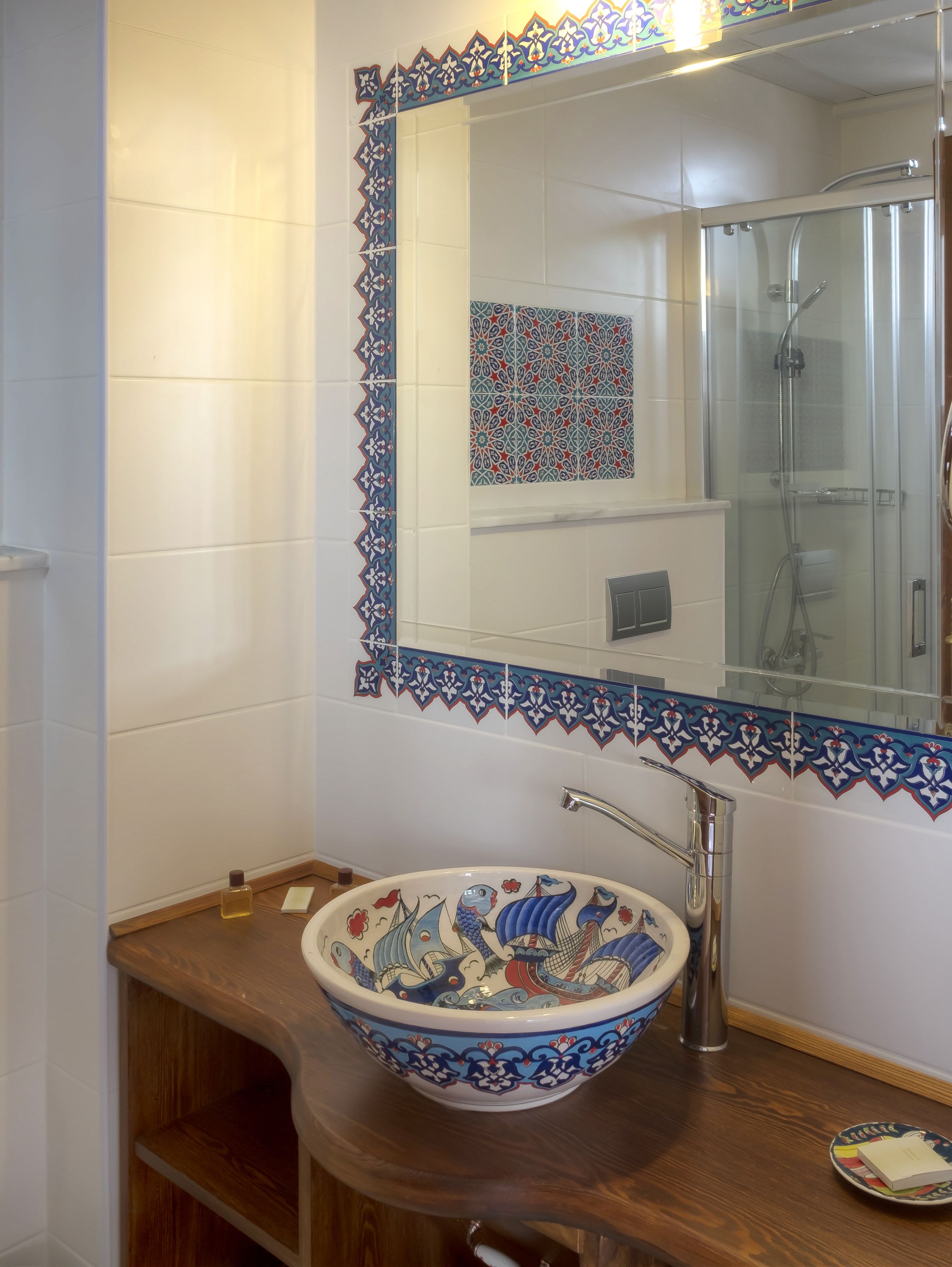 A bathroom with a large mirror, a bowl sink, and a shower enclosure.