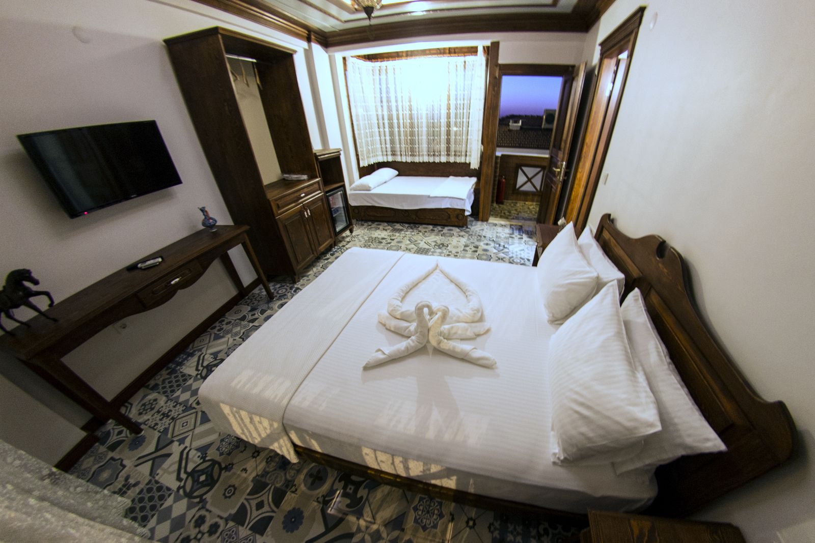 A hotel room with a bed, a TV, a wardrobe, and a bathroom visible through an open door.