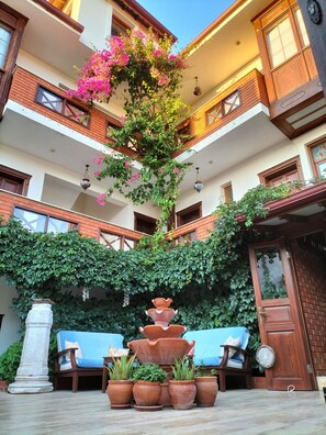 Un patio con una fuente central, plantas en macetas y una zona de estar.