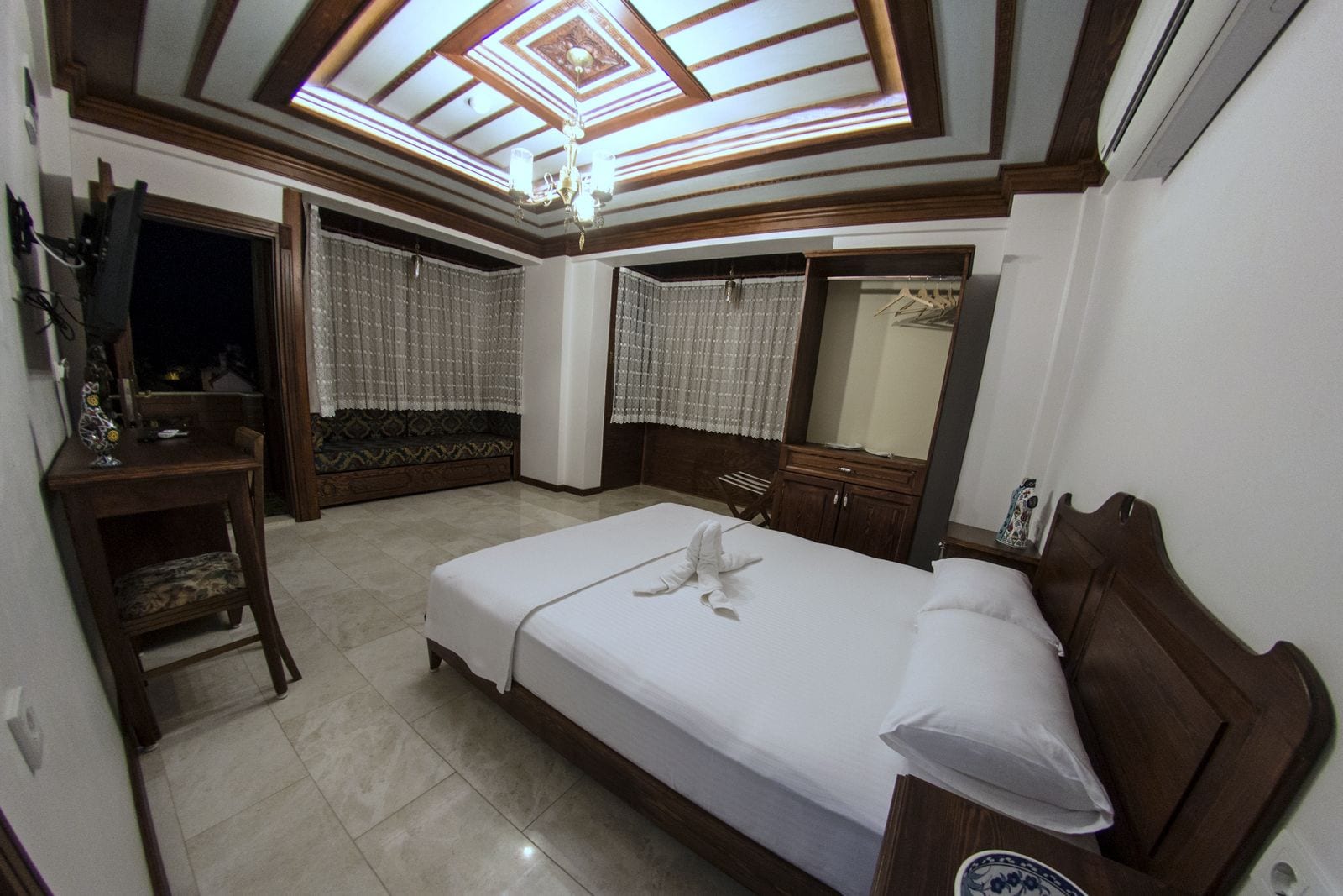 Un dormitorio con cama, cómoda, tocador y un techo con tragaluz.