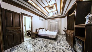 A bedroom with a patterned floor, a bed with white linens, a wooden wardrobe, and a ceiling with a decorative design. - Hotel Mary's House (Selçuk)