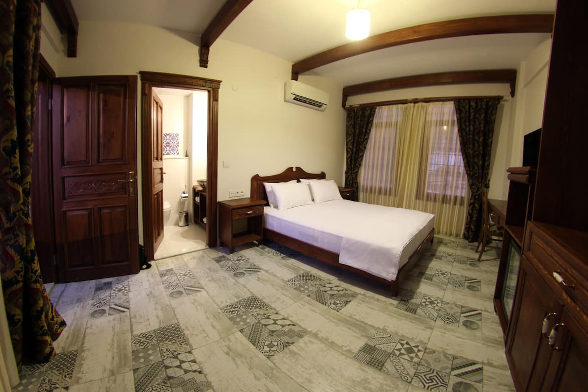 A bedroom with a wooden bed, a nightstand, an air conditioning unit, and patterned floor tiles.