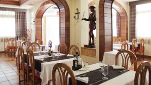 A restaurant with multiple tables, chairs, and a statue of a pirate. - Hotel Teruel (Vinaros)