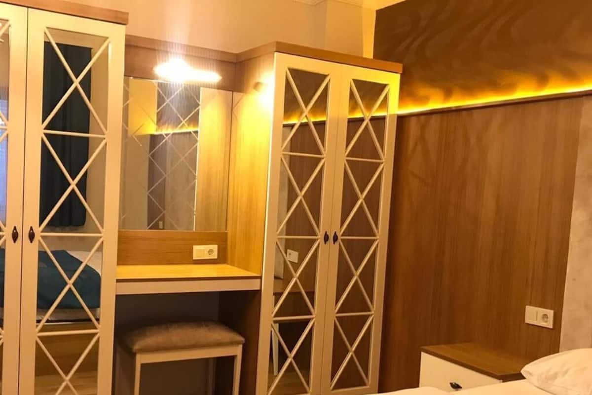 A hotel room with a bed, a desk with a chair, and a wardrobe with glass doors.