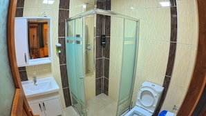 A compact bathroom with a glass-enclosed shower, a toilet, and a sink. - Uzungol Kusva Apart (Çaykara)