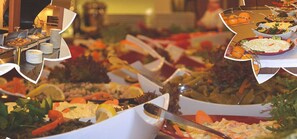 A buffet with various dishes, including salads, fruits, and other food items.