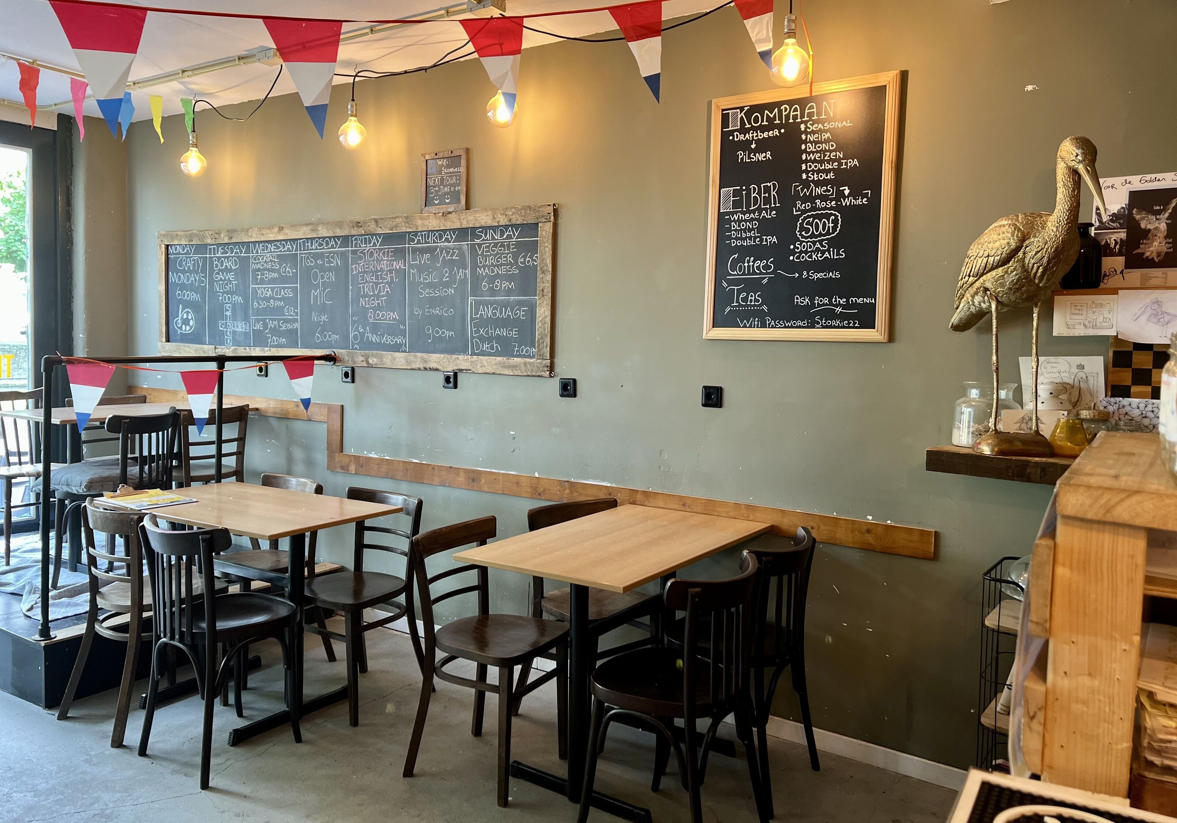 A restaurant interior with wooden tables and chairs, a chalkboard menu, and a decorative bird sculpture.