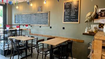 A restaurant interior with wooden tables and chairs, a chalkboard menu, and a decorative bird sculpture.