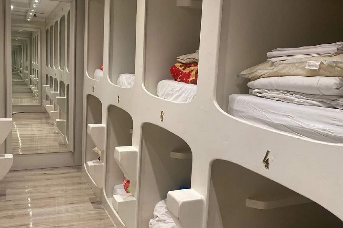 Una habitación de hotel con literas, un baño con espejo y un pasillo con varias habitaciones.