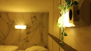 A hotel room with a bed, a wall-mounted air conditioning unit, and a plant with green leaves. - The Golden Stork - Hostel (The Hague)
