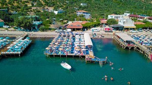 Une zone côtière avec un bateau amarré, une jetée dotée de chaises longues et un petit bateau sur l’eau.